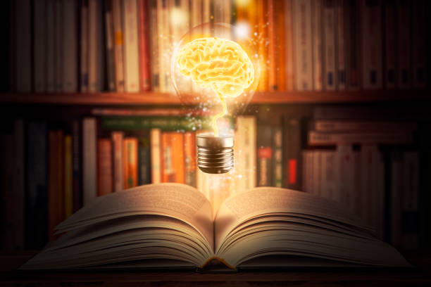 A lit bulb with a glowing brain inside it, standing over an
                    open book in front of a bookshelf